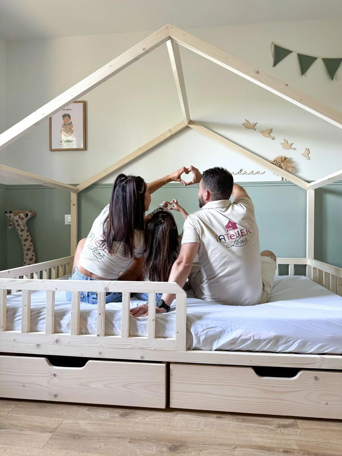 Le fabricant artisanal de l'Atelier de Léna et sa famille assis sur un lit en bois conçu sur mesure.